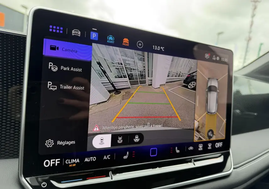Écran tactile intérieur affichant la caméra de recul et l’assistance au stationnement du Volkswagen Tiguan blanc.