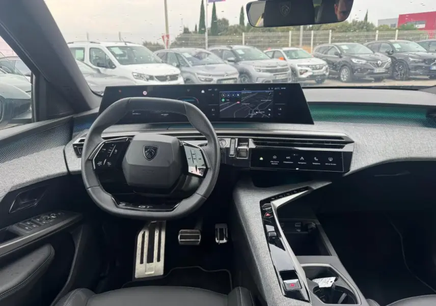Vue intérieure du poste de conduite du Peugeot 5008 Hybrid 145 ch e-DCS6 GT 2025, avec volant compact, écran tactile large et finition noire.