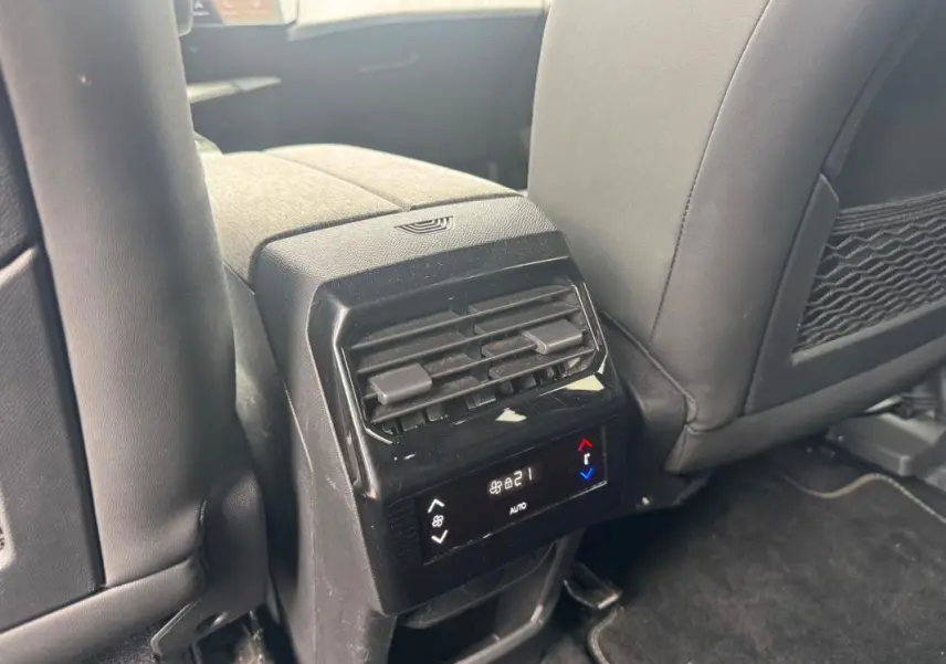 Vue rapprochée de la console centrale arrière du Peugeot 5008 noir, montrant la ventilation et le contrôle de climatisation digital.