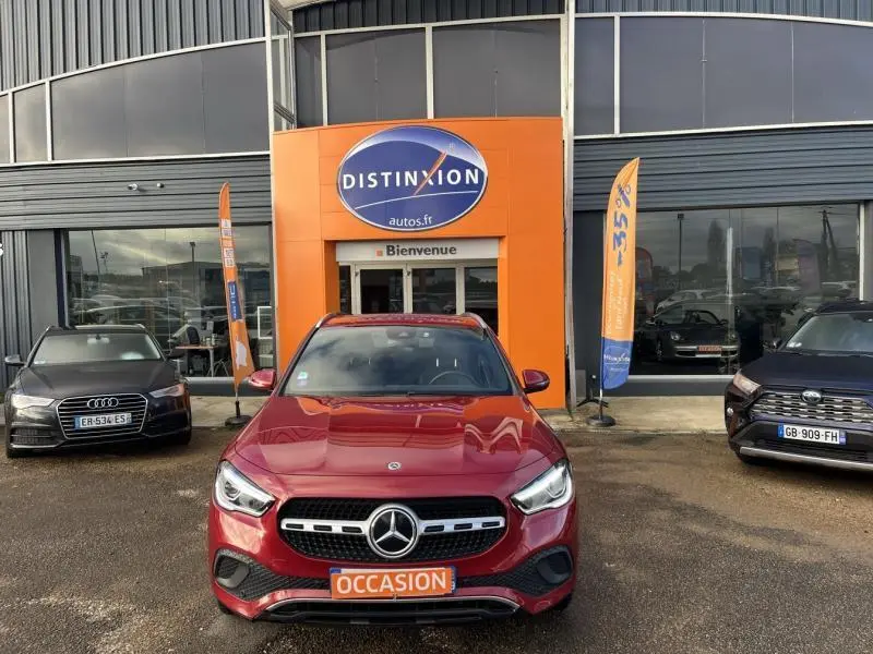 Mercedes GLA 200 Business Line rouge Patagonie métallisé vue de face devant un concessionnaire avec panneau orange "Occasion"