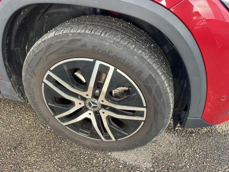 Gros plan sur la roue avant gauche d'une Mercedes GLA rouge Patagonie métallisé avec jante alliage noir et argent.