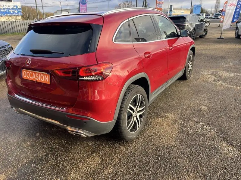 Vue 3/4 arrière droite d'un Mercedes GLA rouge Patagonie métallisé avec vitres arrière teintées et jantes alliage noires.