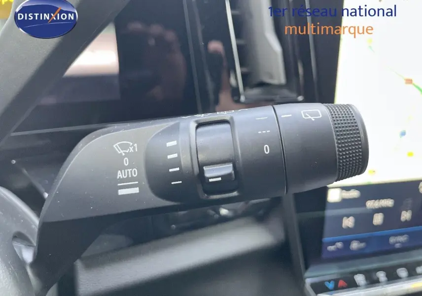 Gros plan sur la commande d’essuie-glace du Renault Austral blanc nacré, avec écran tactile en arrière-plan.