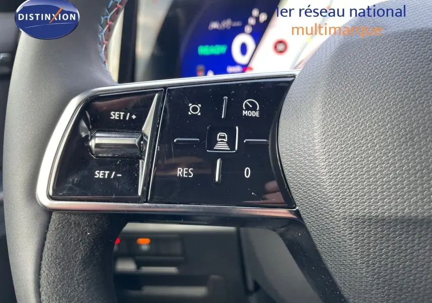 Gros plan sur les commandes au volant du Renault Austral E-Tech hybride 2025, avec affichage numérique en arrière-plan.
