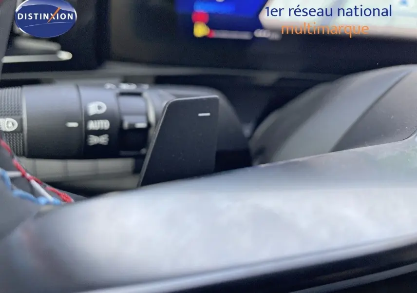 Gros plan sur la palette de changement de vitesse derrière le volant d'un Renault Austral blanc nacré 2025.