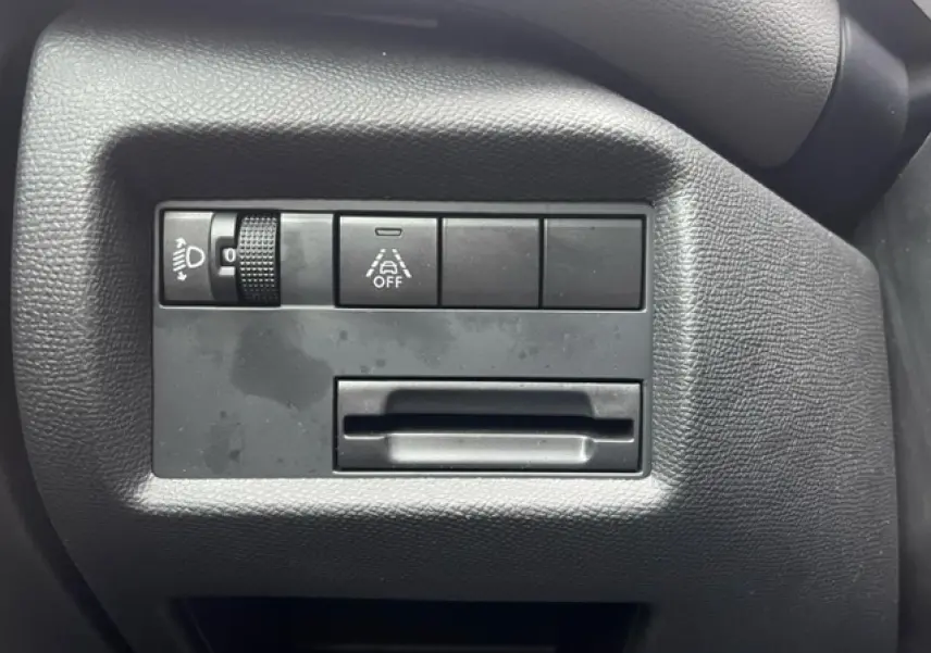 Gros plan sur les commandes de réglage des feux et de l'aide à la conduite du tableau de bord du Citroën C5 Aircross gris.