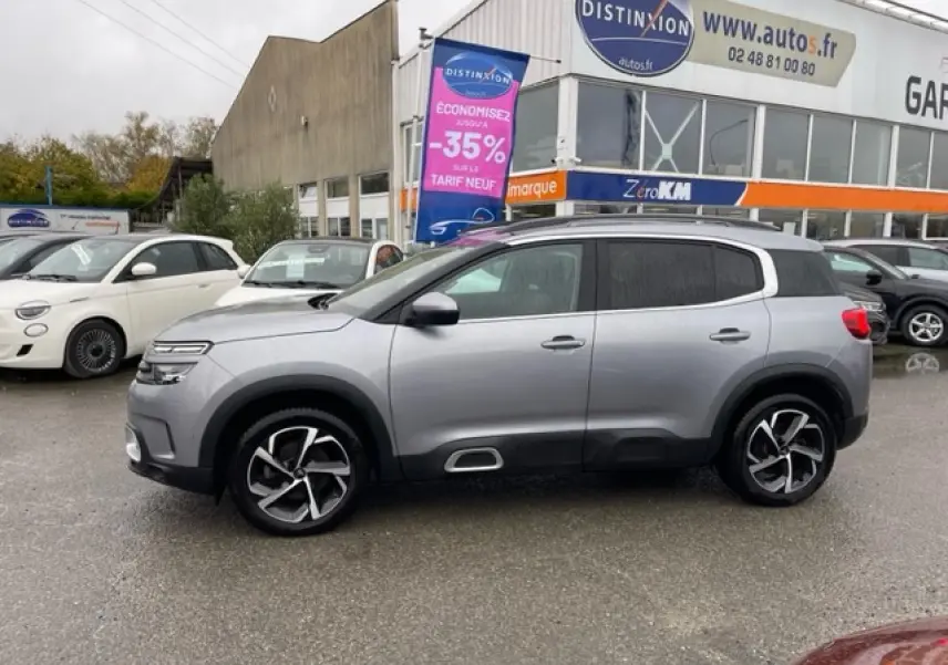 Profil côté gauche d'un Citroën C5 Aircross gris Artense 2021 avec jantes alliage 18'' Swirl sur parking extérieur.
