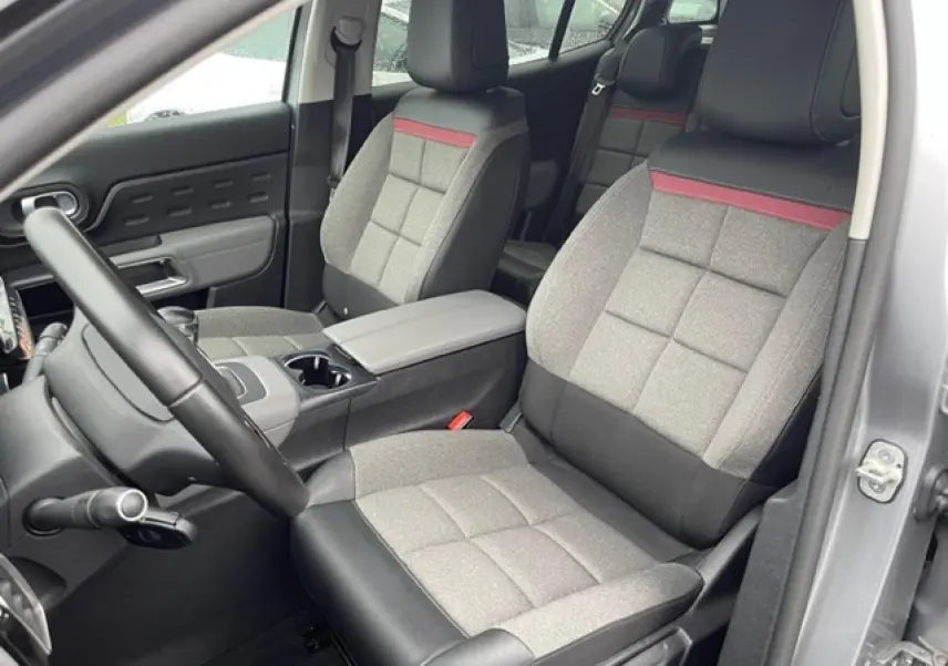 Vue intérieure côté conducteur du Citroën C5 Aircross gris Artense, sièges tissu gris avec bande rouge et cuir noir.