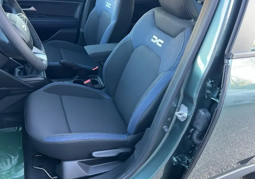 Vue intérieure côté conducteur du Dacia Duster 2025 vert cèdre, sièges bi-matière avec logo distinctif brodé.