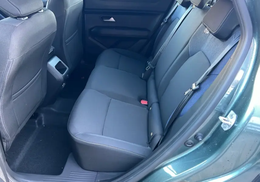Vue intérieure arrière droite du Dacia Duster 2025 vert cèdre, montrant la banquette arrière en tissu noir.