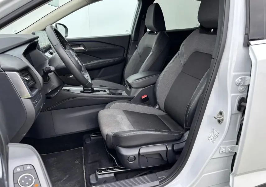 Vue intérieure côté gauche du Nissan Qashqai blanc nacré 2025, montrant les sièges avant en tissu noir et gris.