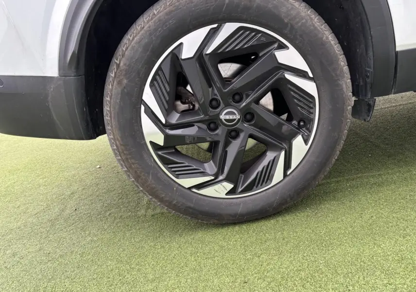 Gros plan sur la roue avant droite du Nissan Qashqai blanc nacré, jante alliage 18 pouces noire et argentée.