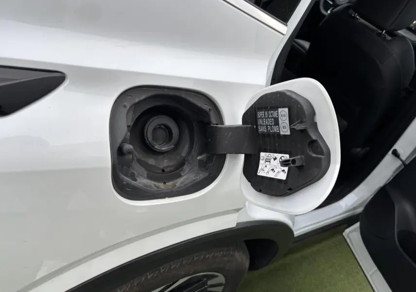 Vue rapprochée de la trappe à carburant ouverte côté gauche d’un Nissan Qashqai blanc nacré avec porte arrière ouverte.