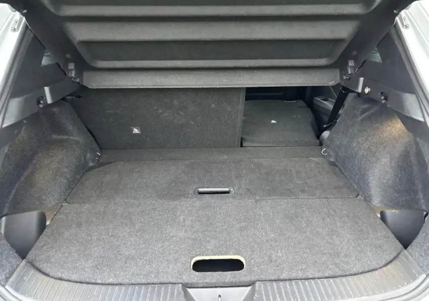 Coffre ouvert du Nissan Qashqai blanc nacré 2025 avec banquette arrière rabattue et plancher plat.