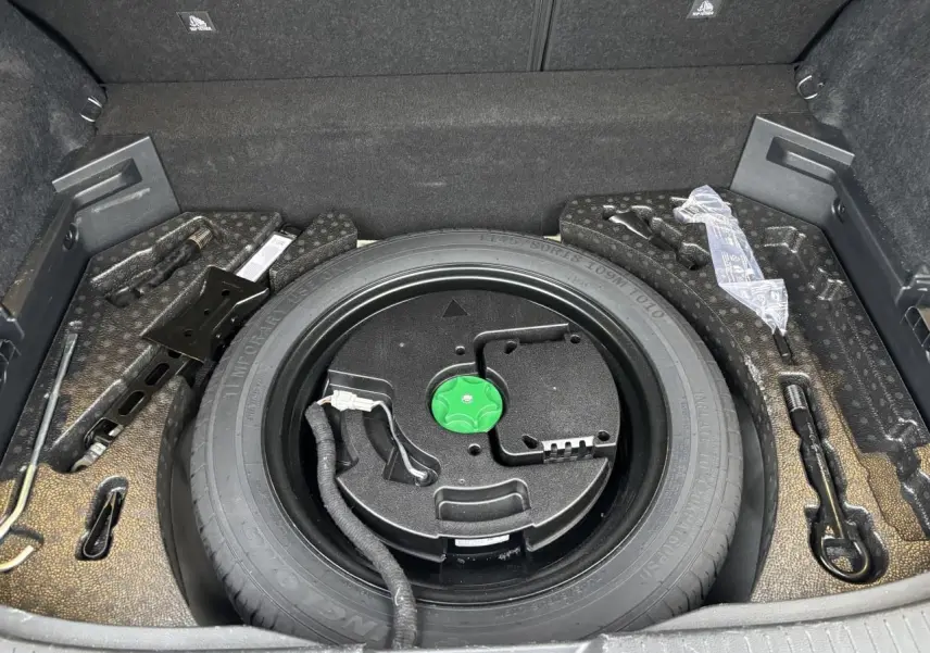 Vue plongeante sur la roue de secours temporaire noire dans le coffre du Nissan Qashqai blanc nacré 2025.