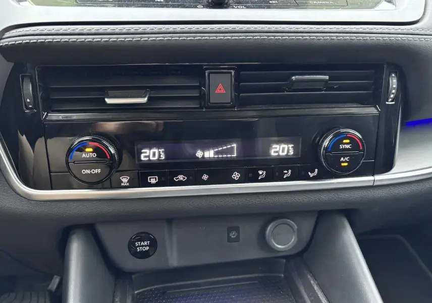 Vue rapprochée de la console centrale noire du Nissan Qashqai blanc nacré 2025, affichant la climatisation automatique bi-zone.