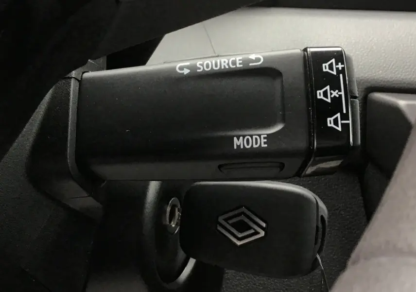Gros plan sur la commande multimédia au volant du Renault Master 2025, avec clé insérée et boutons source et mode visibles.