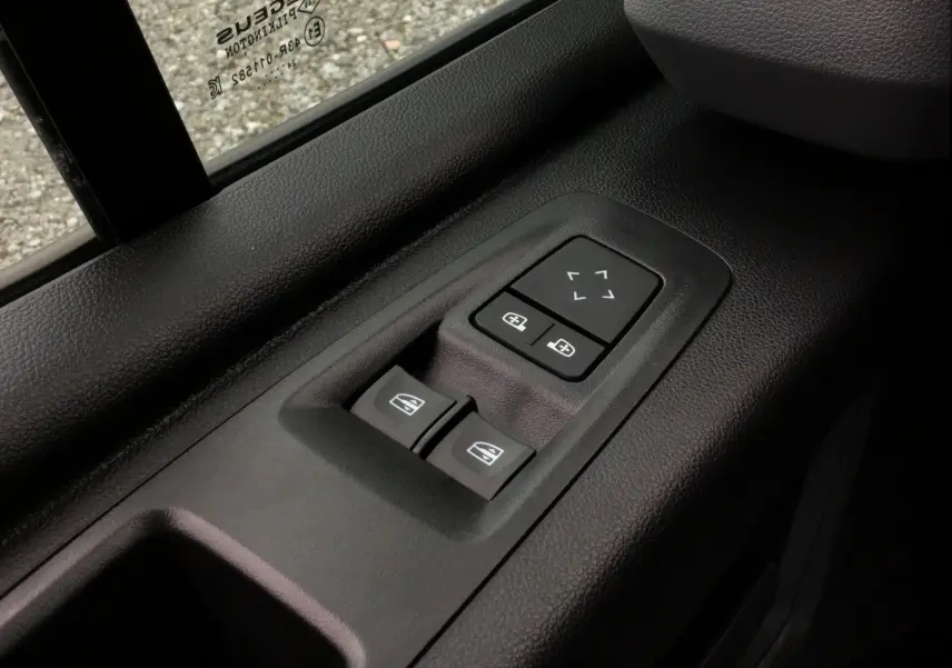 Gros plan sur les commandes électriques des vitres et des rétroviseurs côté conducteur du Renault Master blanc 2025.