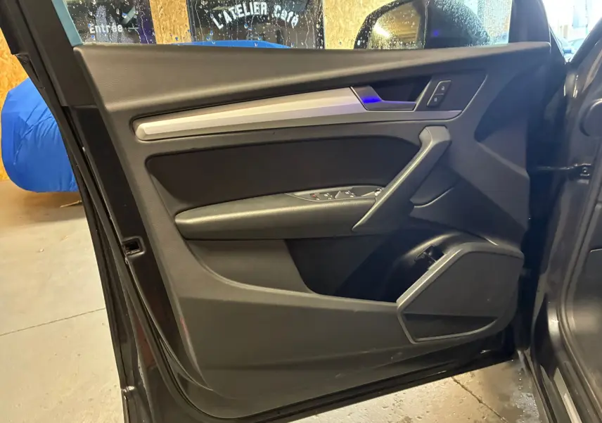 Vue intérieure de la porte avant gauche gris foncé de l'Audi Q5 2024 avec insert argent et commandes électriques.