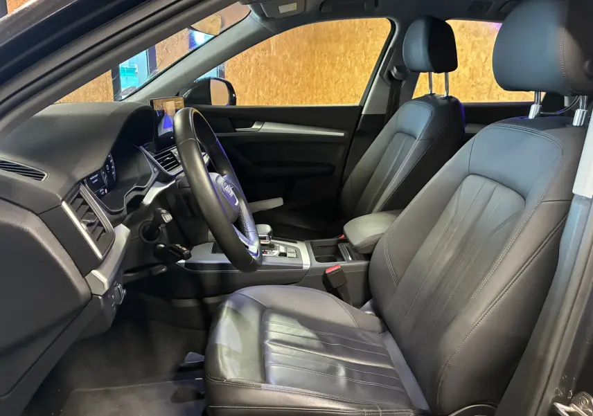 Vue intérieure côté conducteur de l'Audi Q5 2024, sièges en cuir noir et tableau de bord moderne.