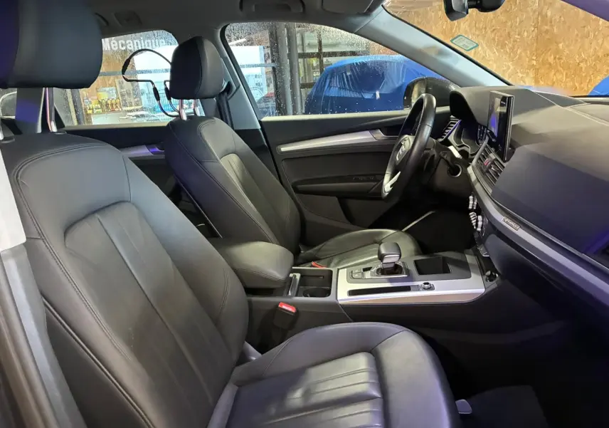 Vue intérieure côté conducteur de l'Audi Q5 2024, sièges en cuir noir et console centrale avec levier de vitesses.