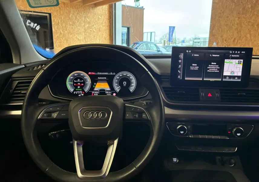 Vue intérieure centrée sur le volant Audi et le tableau de bord numérique du Q5 hybride rechargeable gris 2024.