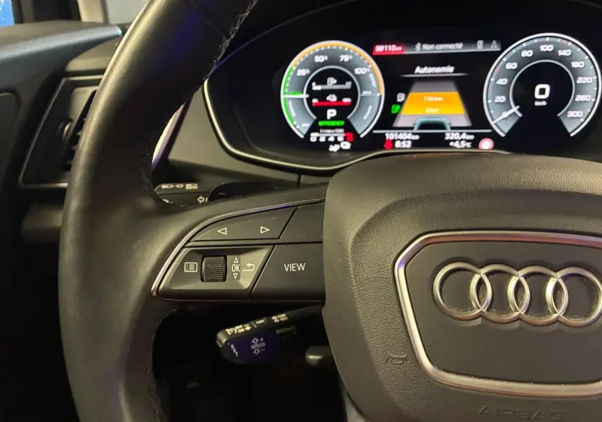 Vue rapprochée du volant cuir noir et du tableau de bord numérique de l'Audi Q5 gris 2024 hybride rechargeable.