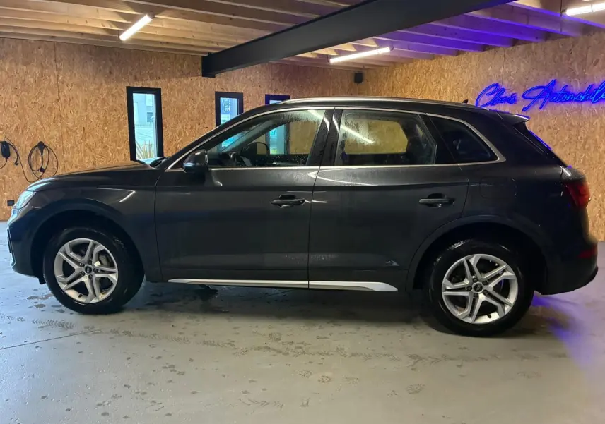 Audi Q5 hybride rechargeable gris en vue de profil côté gauche, avec jantes 5 branches doubles et passages de roue noirs.