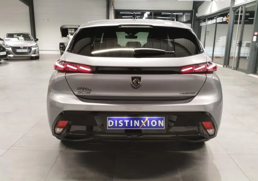 Vue arrière d'une Peugeot 308 gris Artense avec feux arrière LED en forme de griffes et logo lion central.