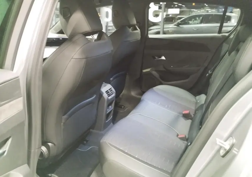 Vue intérieure arrière côté gauche de la Peugeot 308 gris Artense, montrant les sièges et la console centrale avec aérateurs.