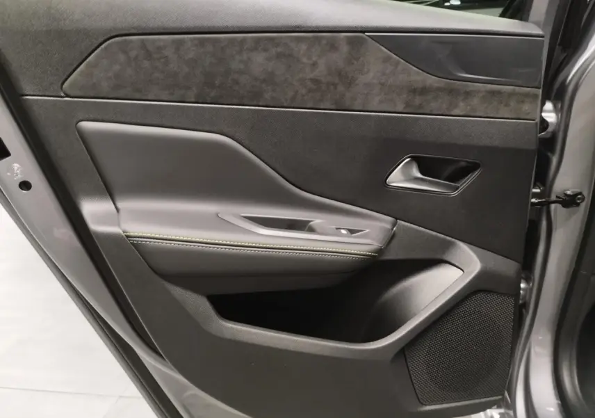 Gros plan sur la porte avant gauche gris Artense de la Peugeot 308 Hybrid avec surpiqûres vert Adamite et haut-parleur intégré.