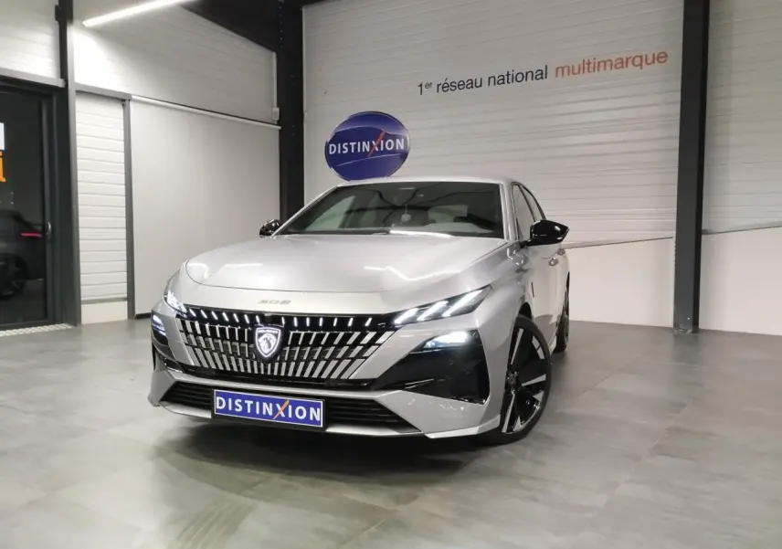 PEUGEOT 308 gris Artense vue 3/4 avant en intérieur, avec calandre lumineuse et jantes noires.