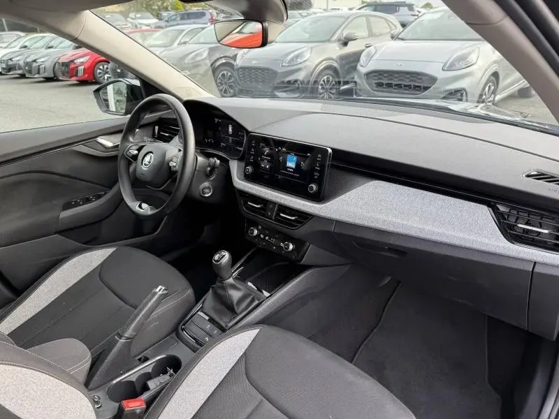 Vue intérieure côté conducteur du Skoda Kamiq 2024 avec tableau de bord moderne et sièges bi-ton gris et noir.