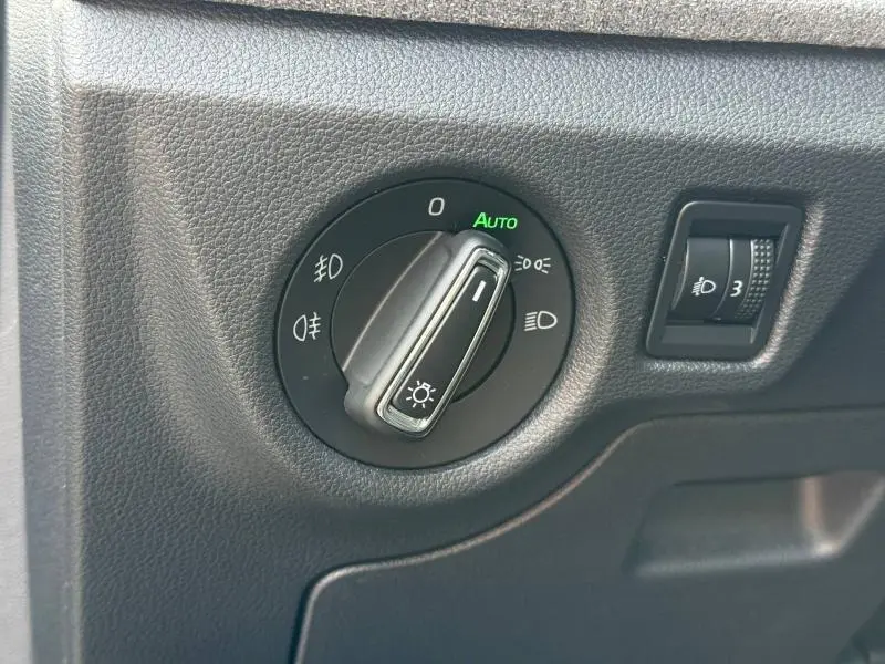 Gros plan sur la commande des phares du Skoda Kamiq 2024, finition noire avec réglage automatique et intensité lumineuse.