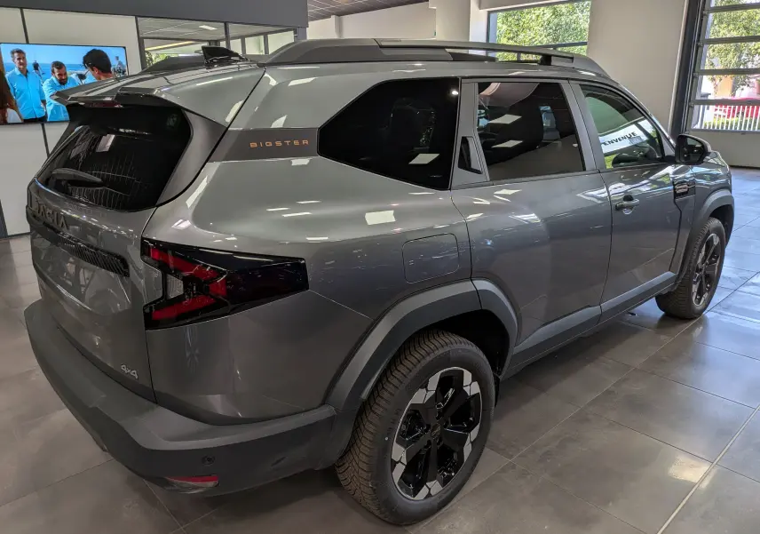 Vue 3/4 arrière droite du Dacia Bigster Hybrid-G 150 4x4 gris schiste avec jantes bi-ton et badges distinctifs.