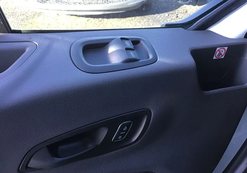 Gros plan sur la porte intérieure côté gauche du Ford Transit Châssis Cabine blanc, avec commandes de vitres et verrouillage.