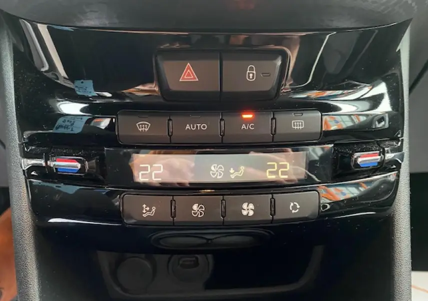 Vue rapprochée du tableau de bord de la Peugeot 2008 blanc, montrant la commande de climatisation automatique bi-zone à 22°C.