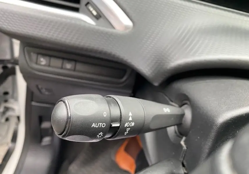 Gros plan sur la commande des phares avec fonction auto dans l'habitacle d'une Peugeot 2008 blanche de 2018.