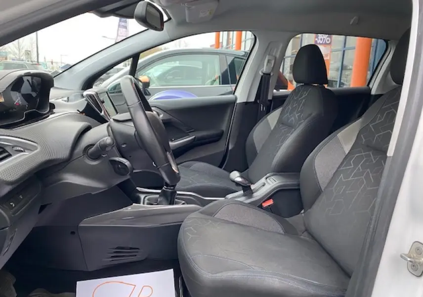 Intérieur avant du Peugeot 2008 blanc, montrant les sièges tissu noir et gris et le tableau de bord moderne côté conducteur.