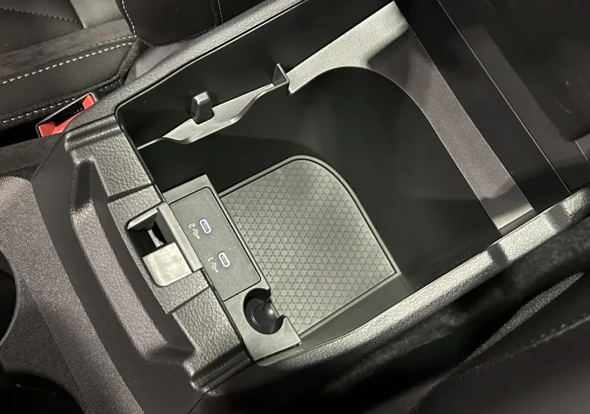 Vue rapprochée de la console centrale ouverte du Nissan Qashqai 2025, avec ports USB et intérieur noir.