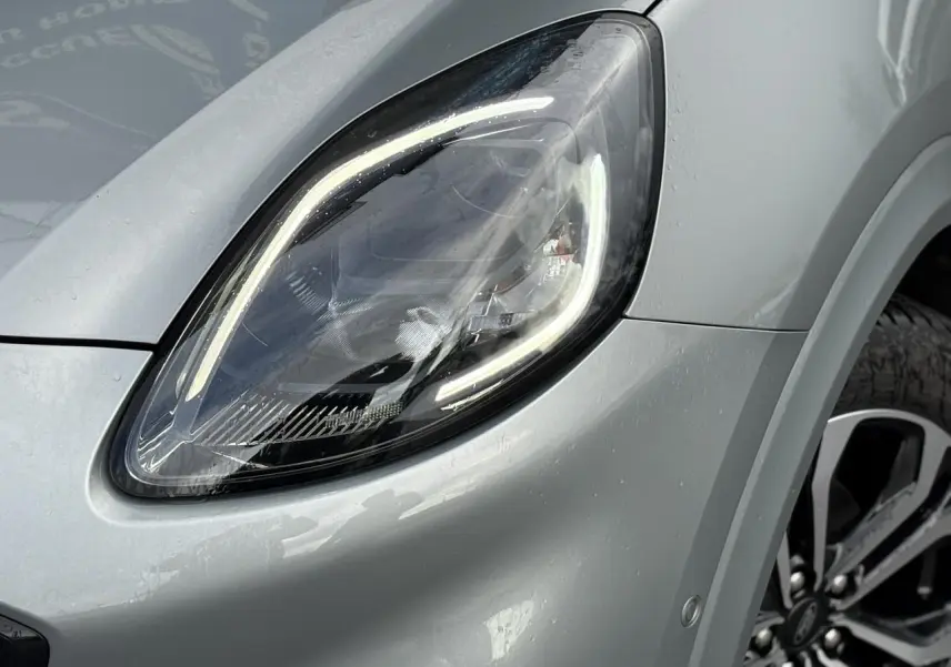 Gros plan sur le phare avant gauche et la jante alliage 17 pouces du Ford Puma gris Solar 2023.