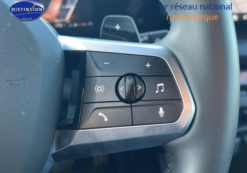 Gros plan sur les commandes multifonctions au volant d'une BMW Série 1 blanche, avec boutons de volume et appels.