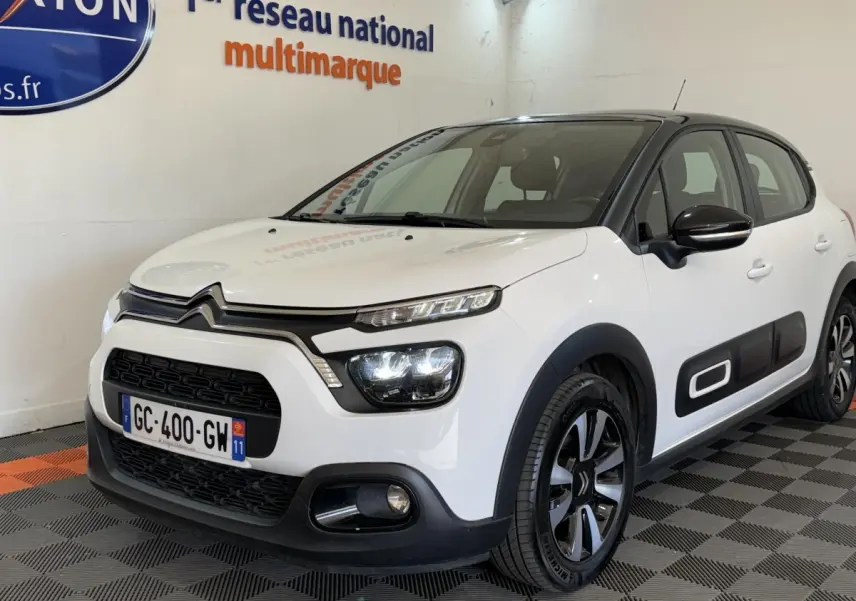 Citroën C3 blanche vue 3/4 avant droit, avec protections latérales noires et jantes alliage distinctives.