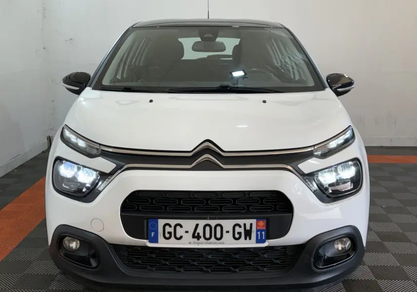 Vue frontale d'une Citroën C3 blanche avec phares LED allumés et calandre noire distinctive.