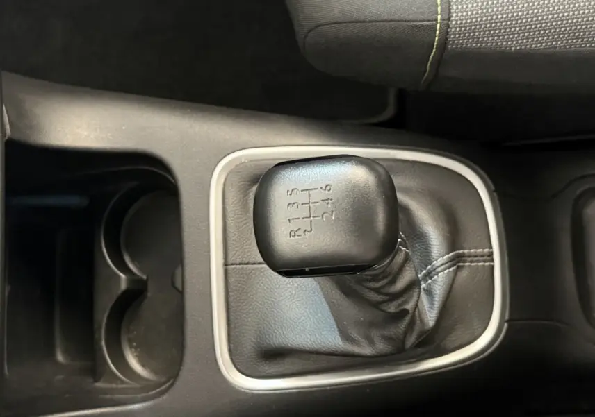 Gros plan sur le levier de vitesse manuel noir de la Citroën C3 blanche, entouré de garniture grise et console noire.