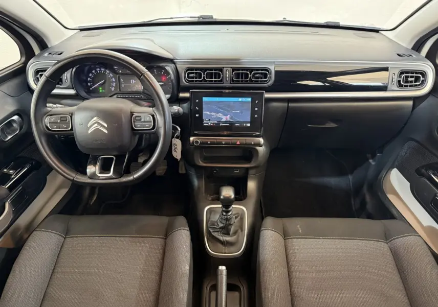 Vue intérieure avant de la Citroën C3 blanche 2021, tableau de bord noir avec écran tactile et volant cuir multifonctions.