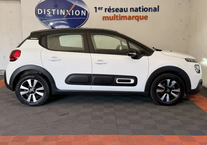 Profil droit d'une Citroën C3 blanche 2021 avec protections latérales noires et jantes distinctives bicolores.