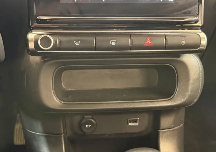 Détail du tableau de bord noir de la Citroën C3 2021, avec boutons de contrôle et prise 12V visible.
