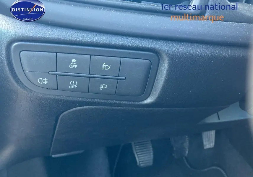 Gros plan sur les commandes d'éclairage et de sécurité sous le tableau de bord d'une FIAT TIPO bleu 2024.