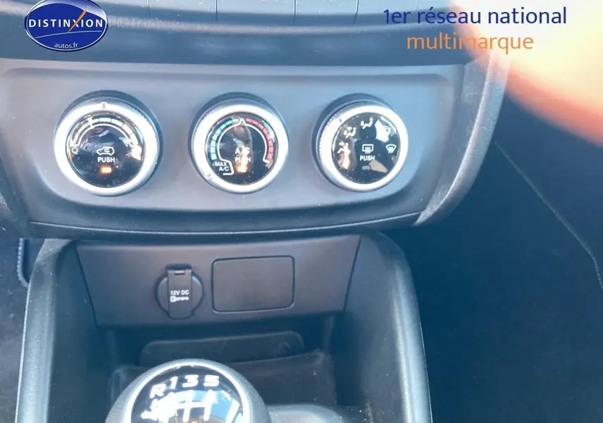 Gros plan sur la console centrale du Fiat Tipo bleu 2024, mettant en valeur les commandes de climatisation et le levier de vitesse manuel.